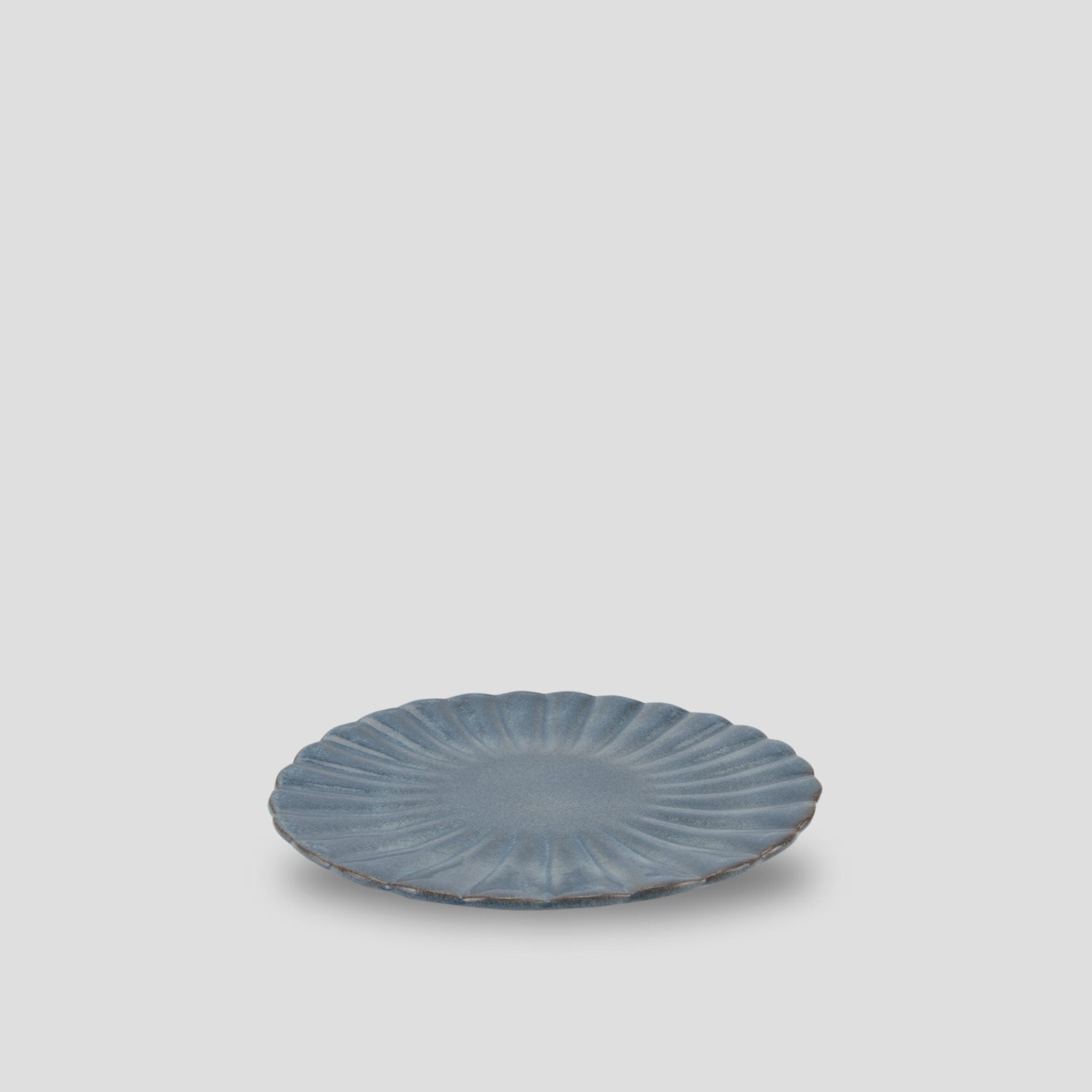 A blue terracotta salad plate with a fluted design.