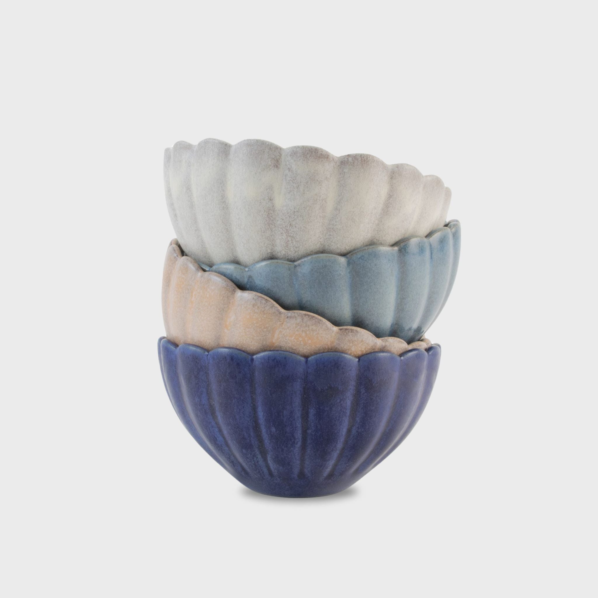A stack of three terracotta bowls in blue, white, and pink colors, with a textured exterior.