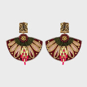 Pair of decorative earrings with gold, green, and pink details on a light gray background