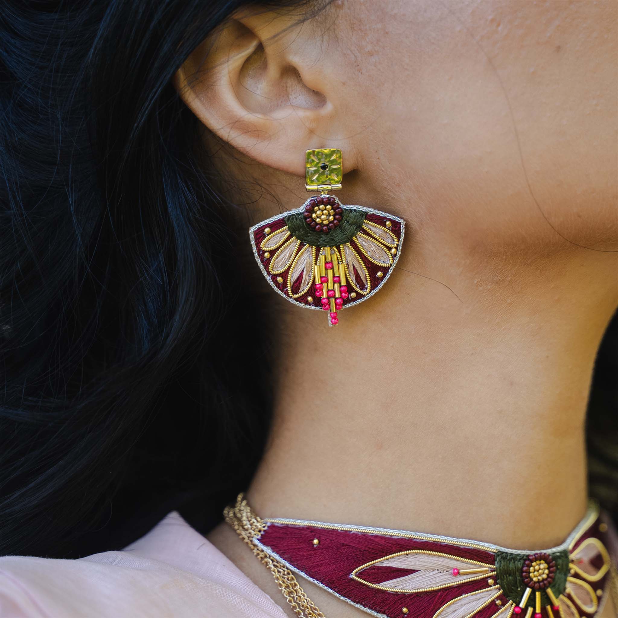 Close-up of a person wearing an ornate earring with intricate designs.