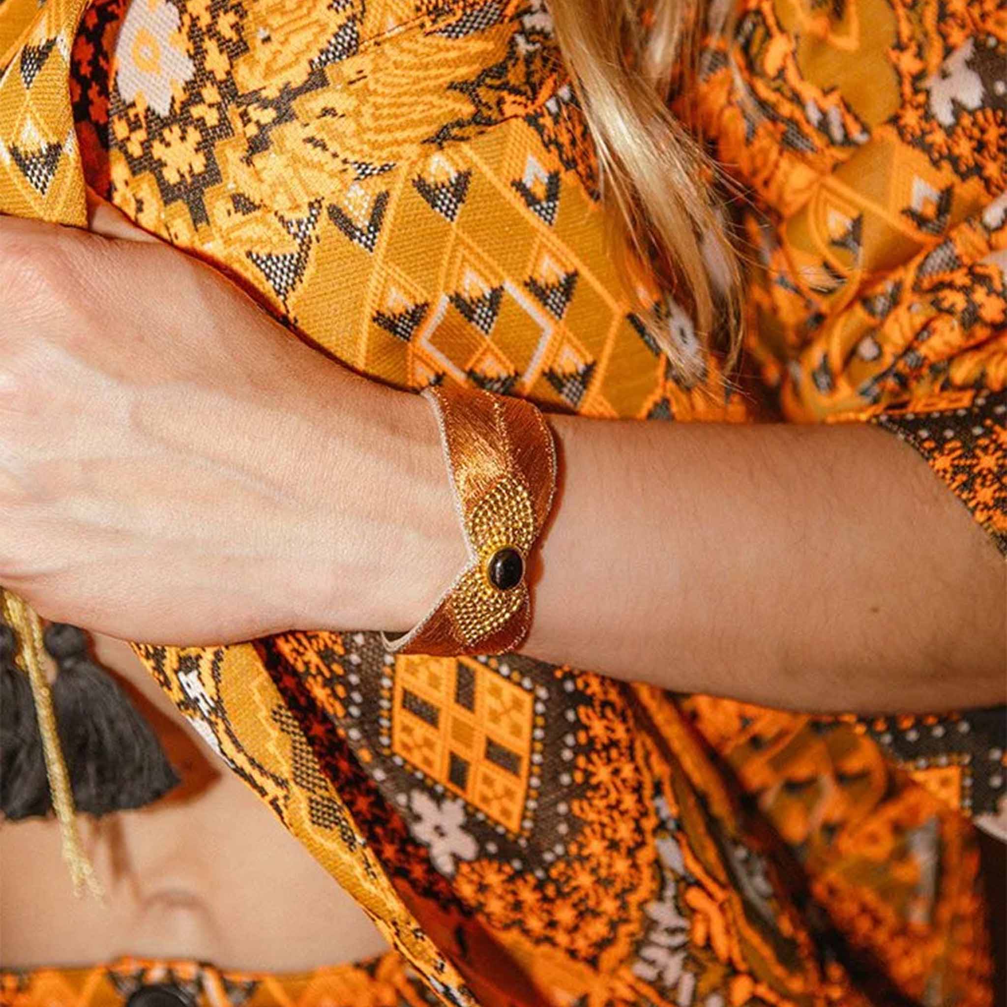 Person wearing a patterned outfit with a focus on a bracelet.