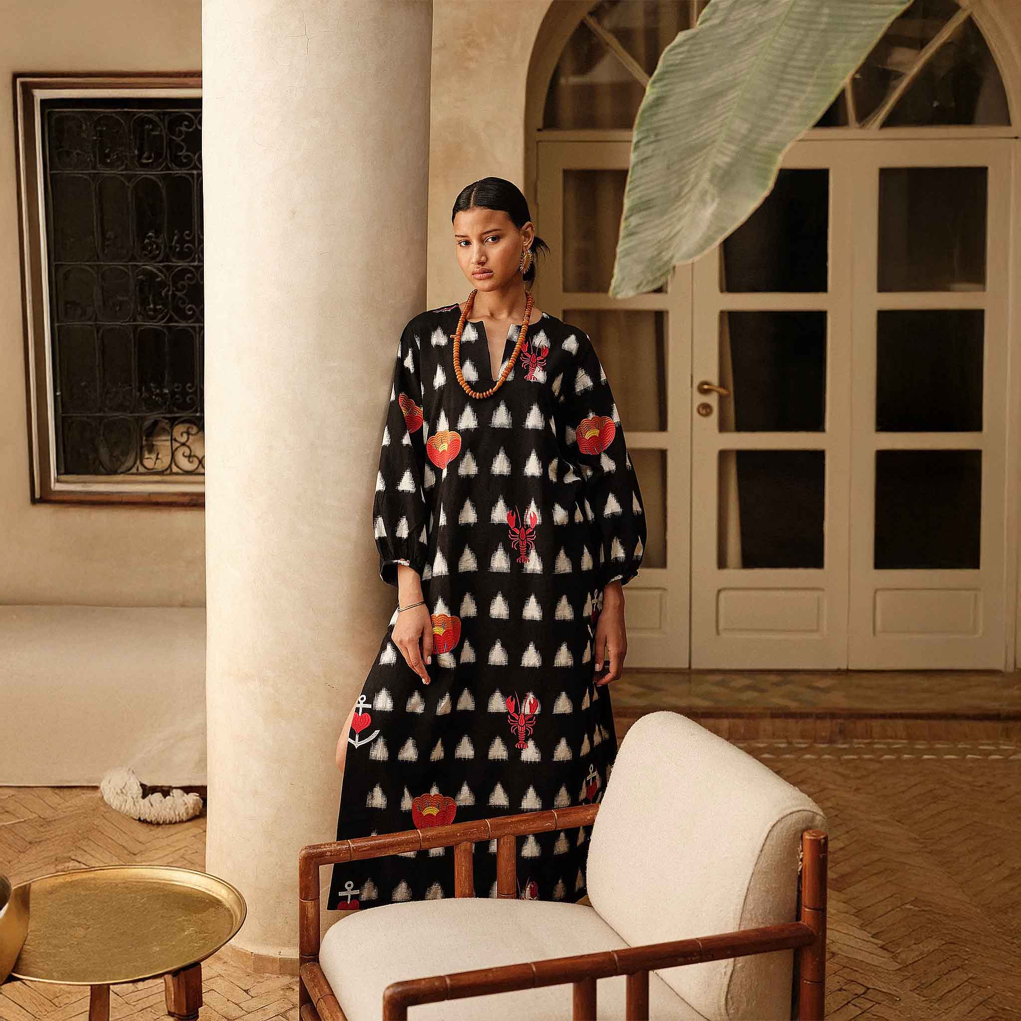 Model in the Gondi Black Kaftan standing in a sunlit courtyard interior