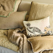Decorative pillows and blanket on a sofa with a bird design