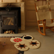 Rug with floral design in front of a fireplace and rocking chair.