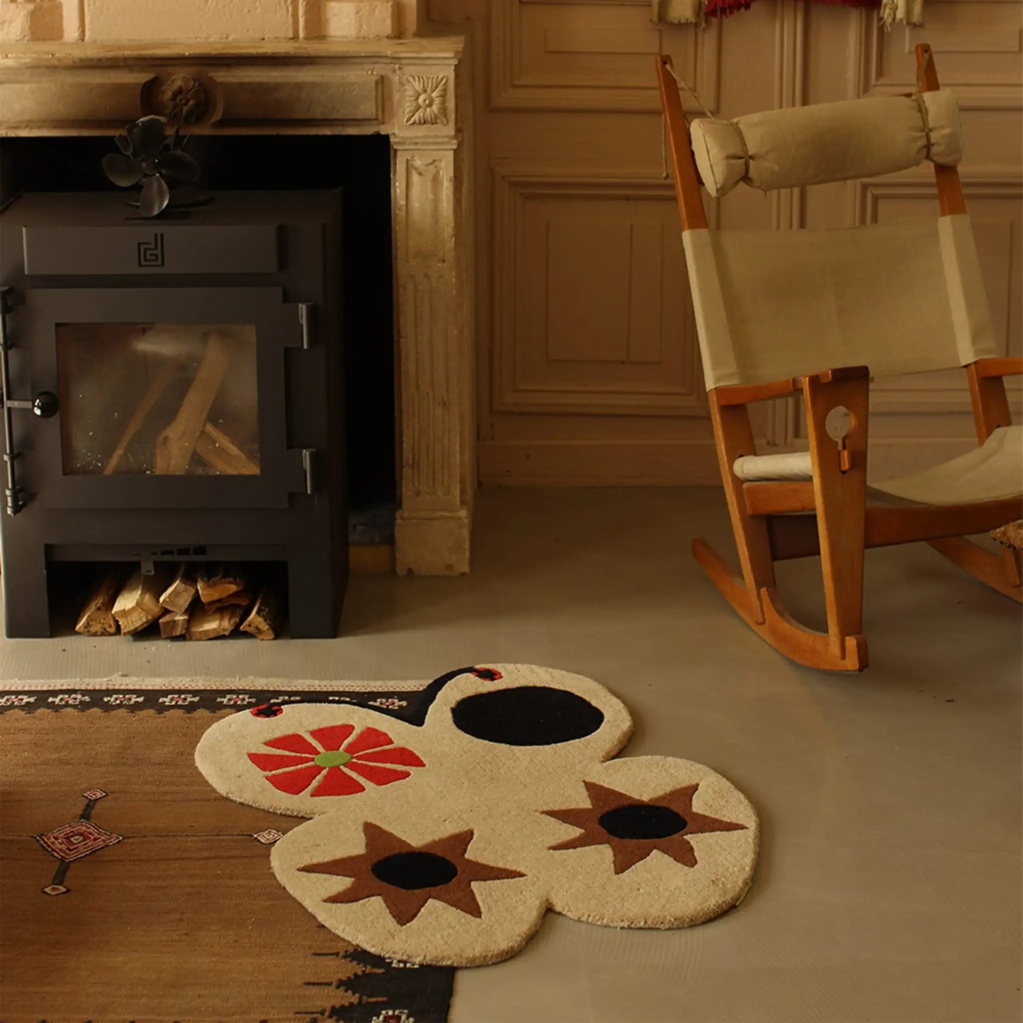 Rug with floral design in front of a fireplace and rocking chair.