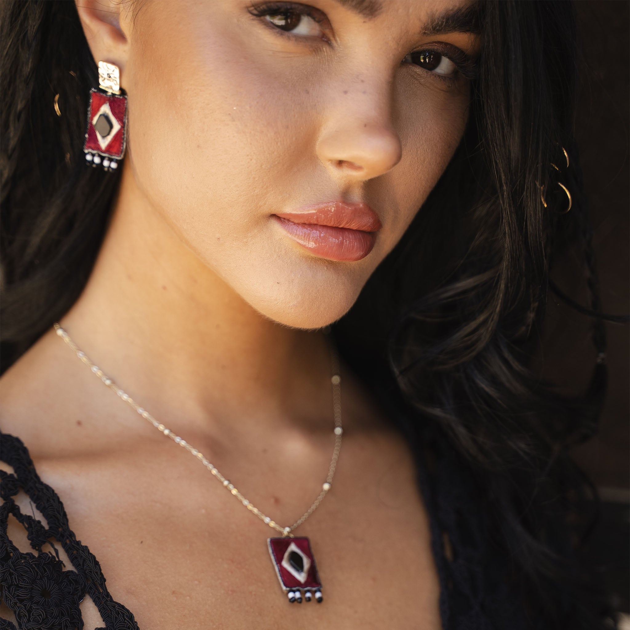 Close-up of a woman wearing a necklace and earrings with a blurred background
