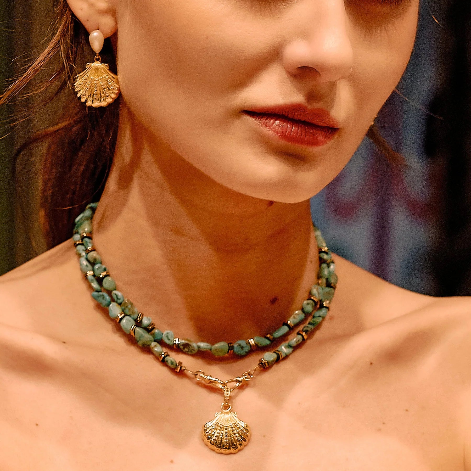 Close-up of a woman wearing gold earrings and necklaces with a blurred background