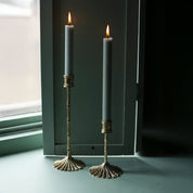 Brass bamboo candle holders with green taper candles by a window