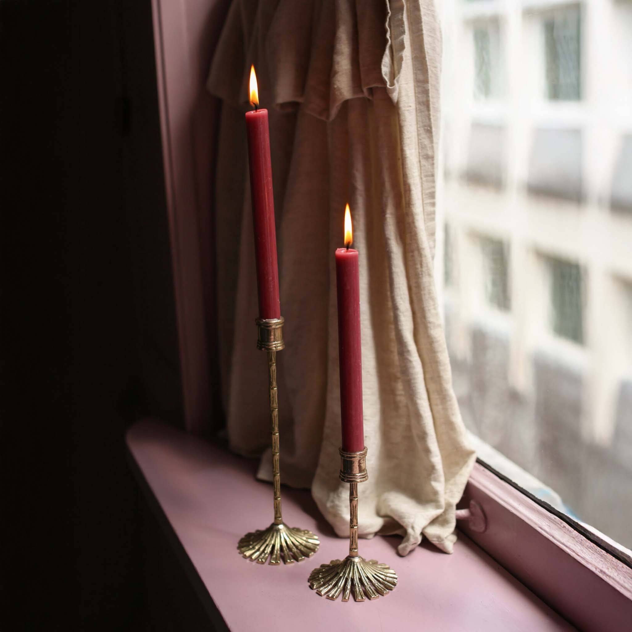 Brass bamboo candle holders with red tapers on a windowsill