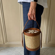 Woman carrying the Basket Handbag in woven cane with brown leather handle