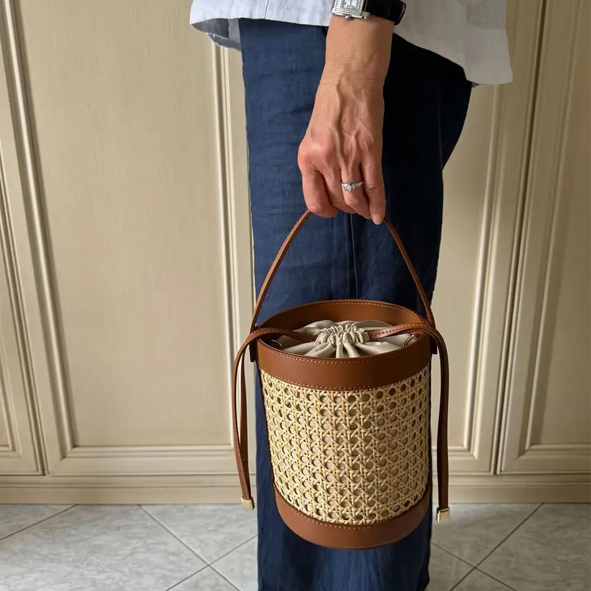 Woman carrying the Basket Handbag in woven cane with brown leather handle