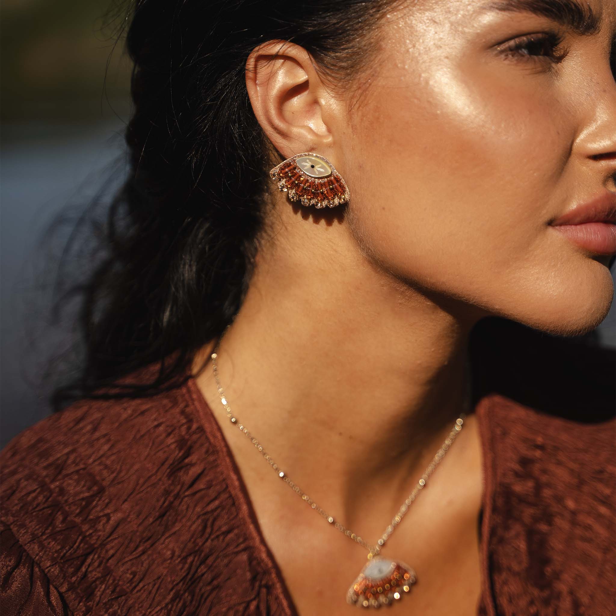 Close-up of a woman wearing a necklace and earrings with a blurred background