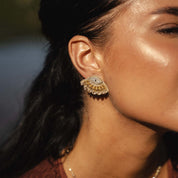 Close-up of a woman wearing a gold and diamond earring with a blurred background
