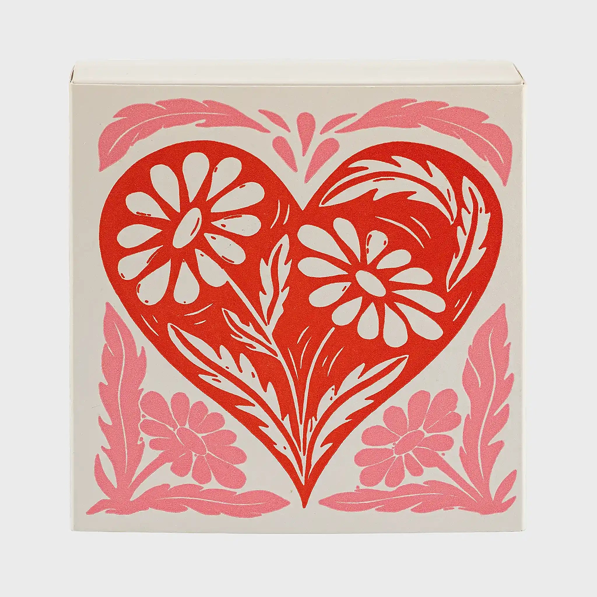 Vista frontal de la caja de fósforos Heart Box de Aura Collective, con el mismo diseño de corazón rojo y flores en rosa.