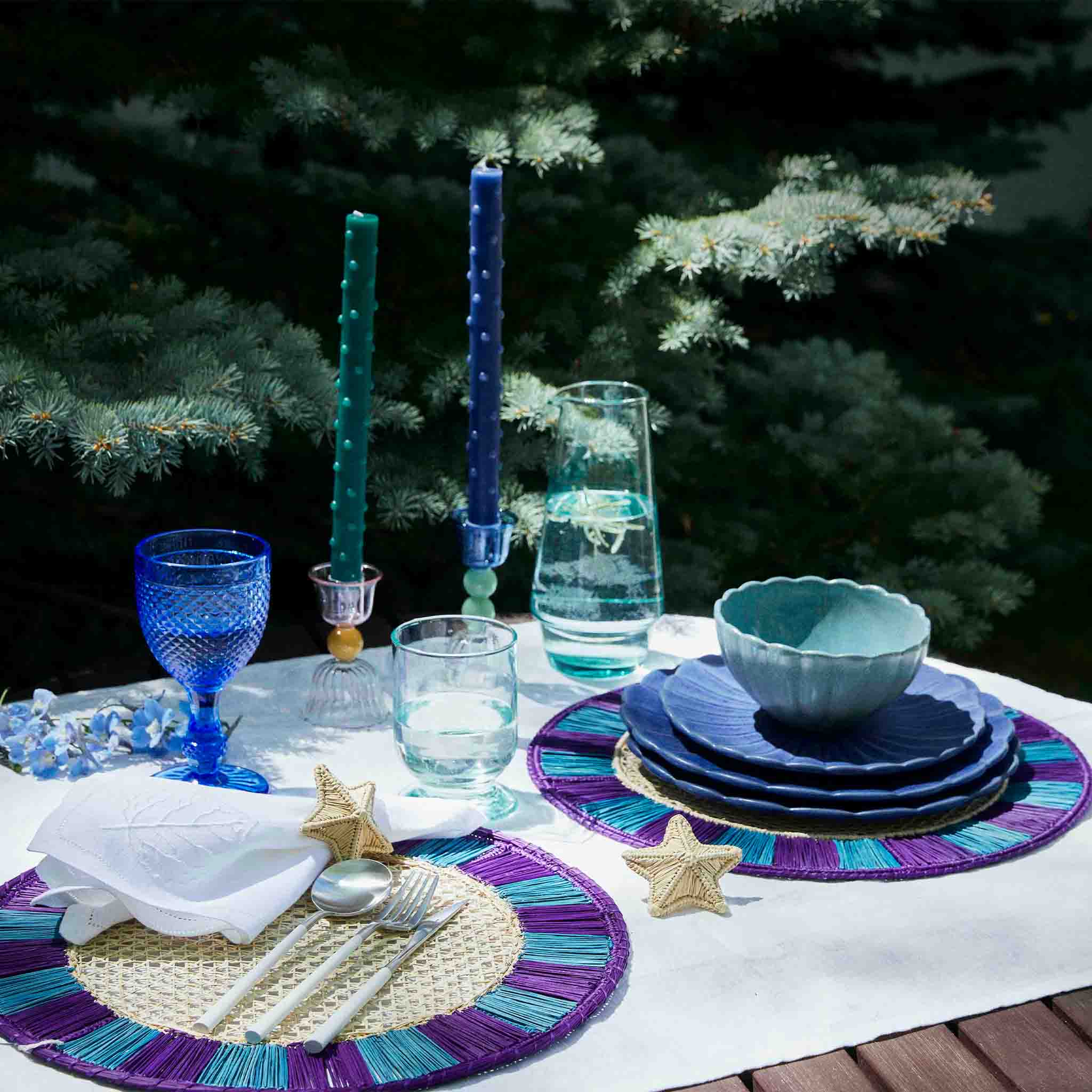 A table arrangement with dinnerware, glasses, and decorations. 