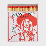 Foto de producto de la caja de fósforos Saint No de Aura Collective: ilustración en rojo de una mujer con sombrero fumando, con el texto Saint No, Out West U.S.A. y Wake with the sun in your eyes.