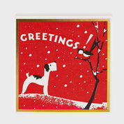 Foto de producto de la caja de fósforos Season's Greetings de Aura Collective: fondo rojo con marco dorado, un perro terrier mirando un pájaro sobre un árbol nevado y el texto Greetings!.