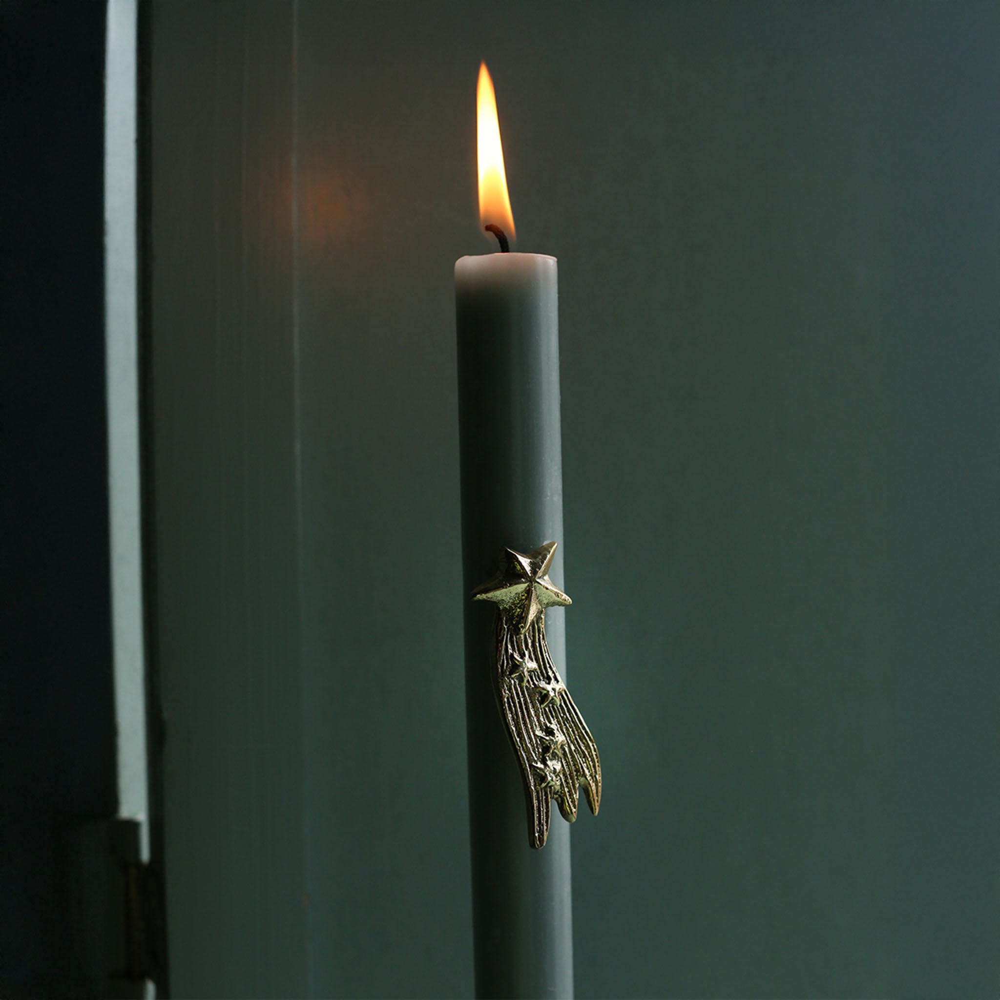 Supernova Star Candle Pin in brass on a dark green taper candle